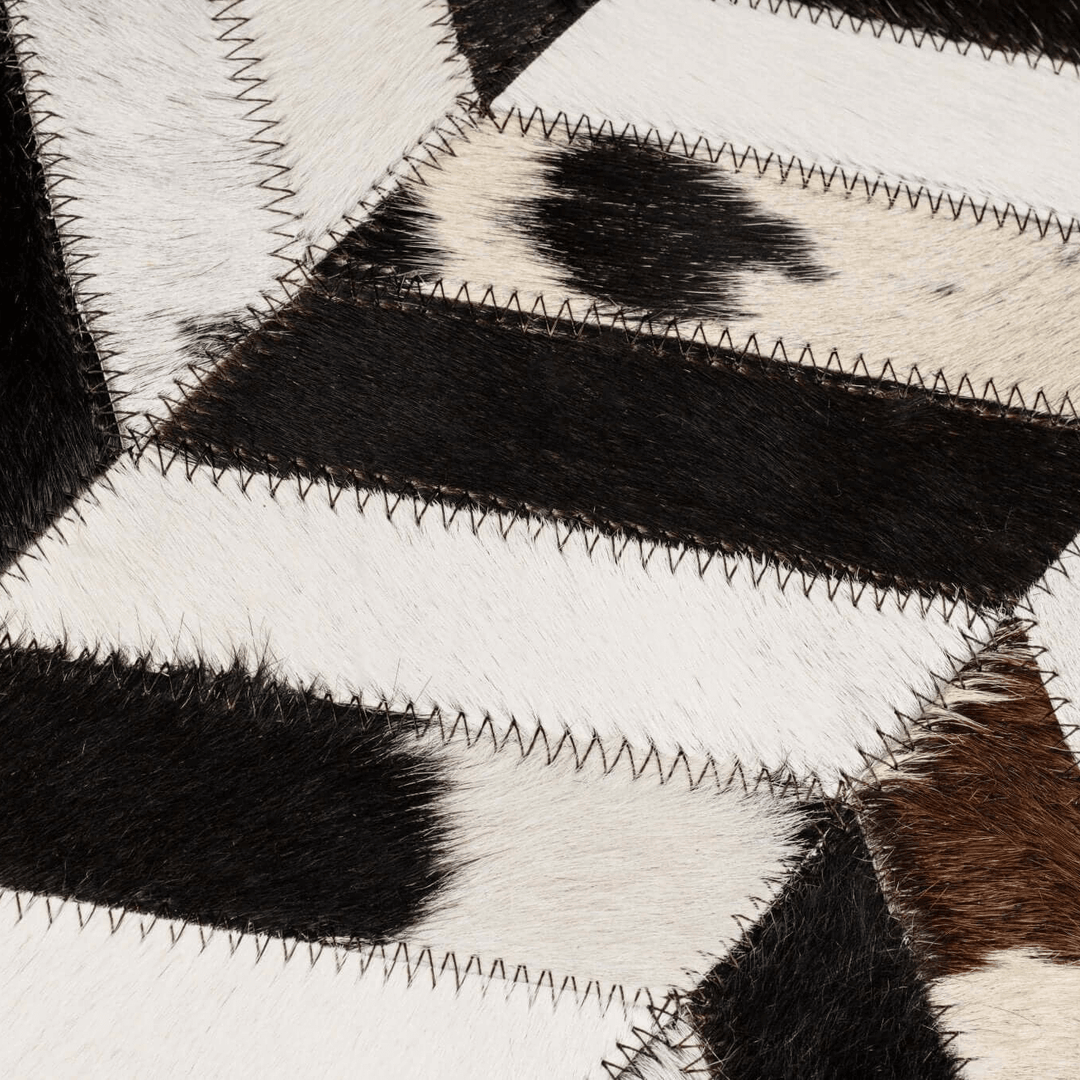 Close-up of a cowhide pillow with black, white, and brown patches.