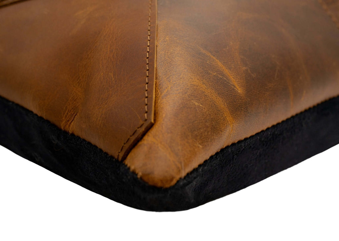 Close-up of a brown leather pillow with visible stitching on a white background