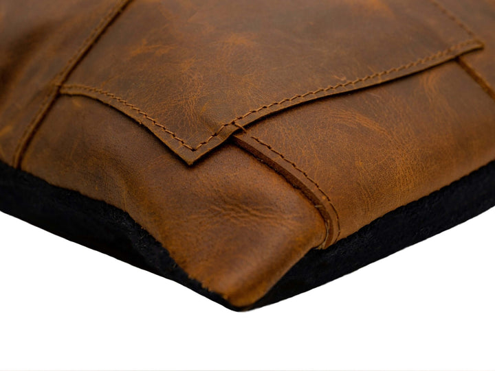 Close-up of a brown leather pillow with stitching details on a white background