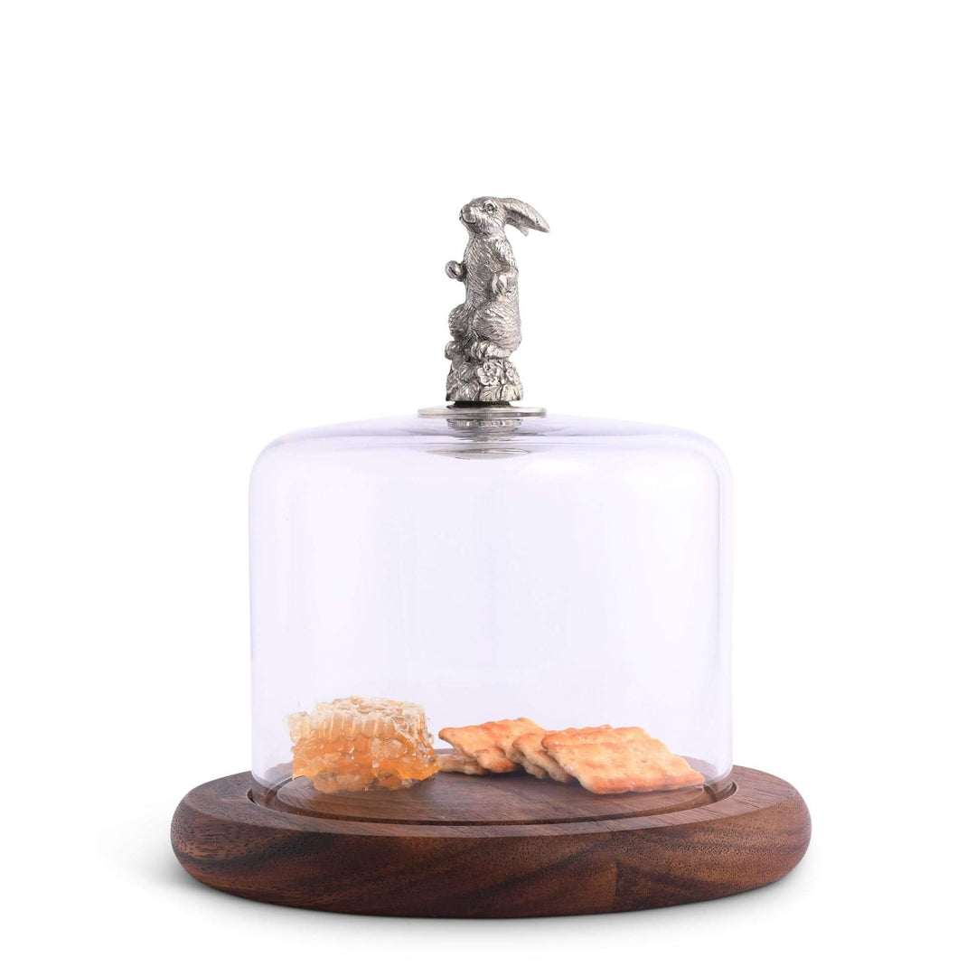 Decorative glass dome with wooden base holding snacks on a white background
