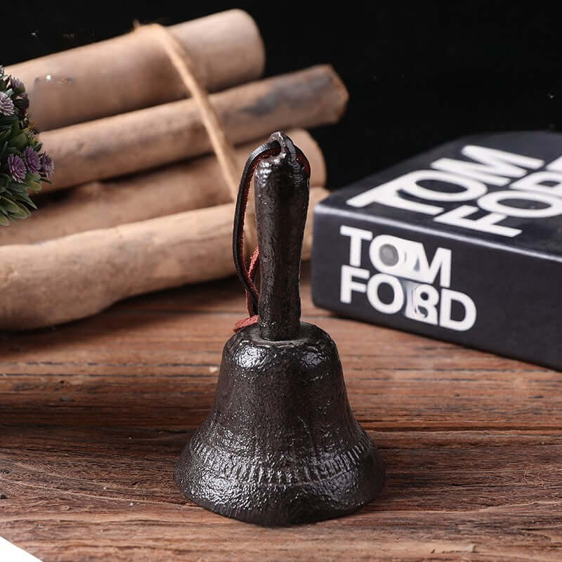 Black bell on a wooden surface with a blurred Tom Ford product in the background