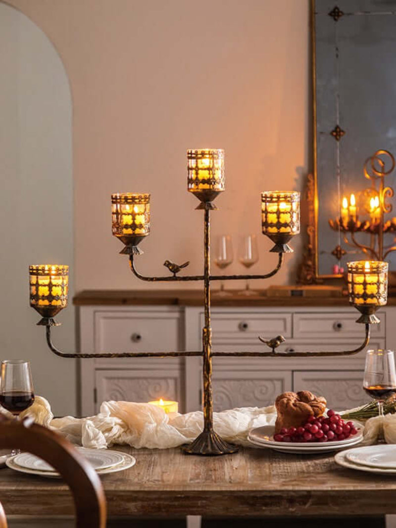 Antique amber glass votive candle holder centerpiece on dining table with glowing candles and elegant dinner setting.