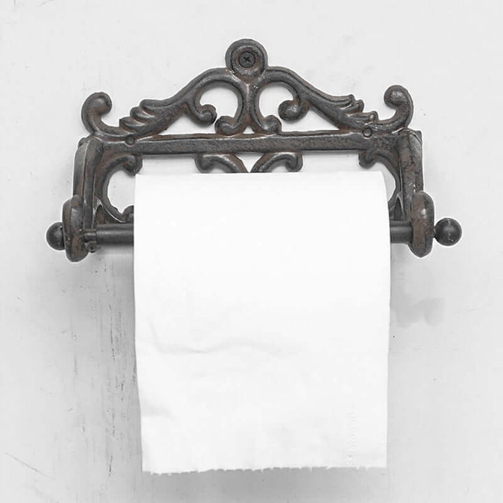 Decorative metal toilet paper holder with a roll of toilet paper on a white background
