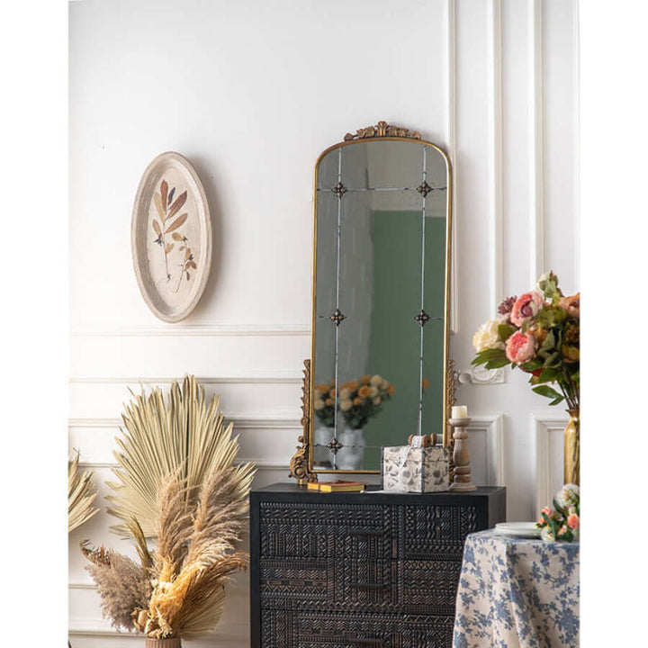 Vintage arched wall mirror with antique gold frame and floral detailing in an elegant room setting.