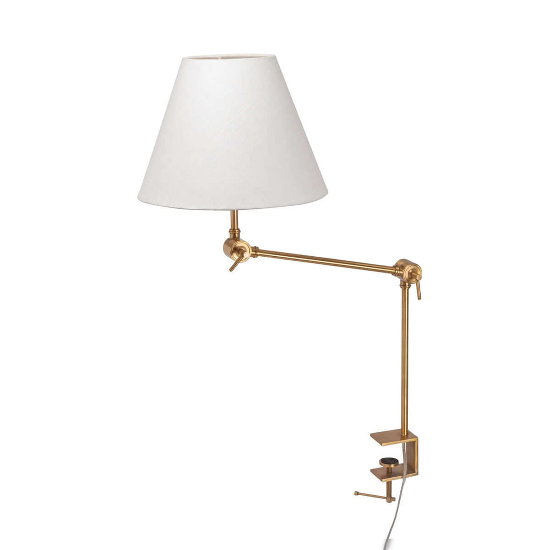 Wall-mounted lamp with white shade and gold arm on a white background