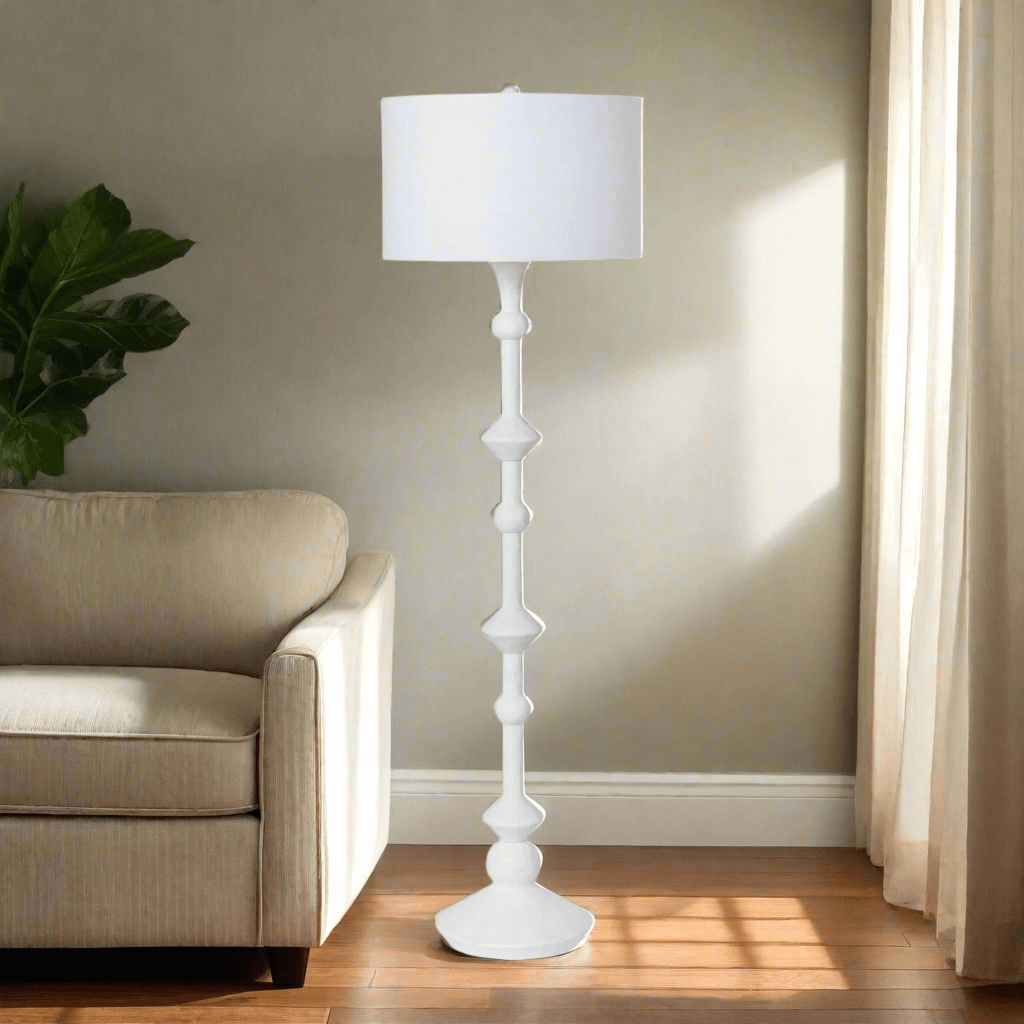 White floor lamp in a living room setting with a beige armchair and plant.