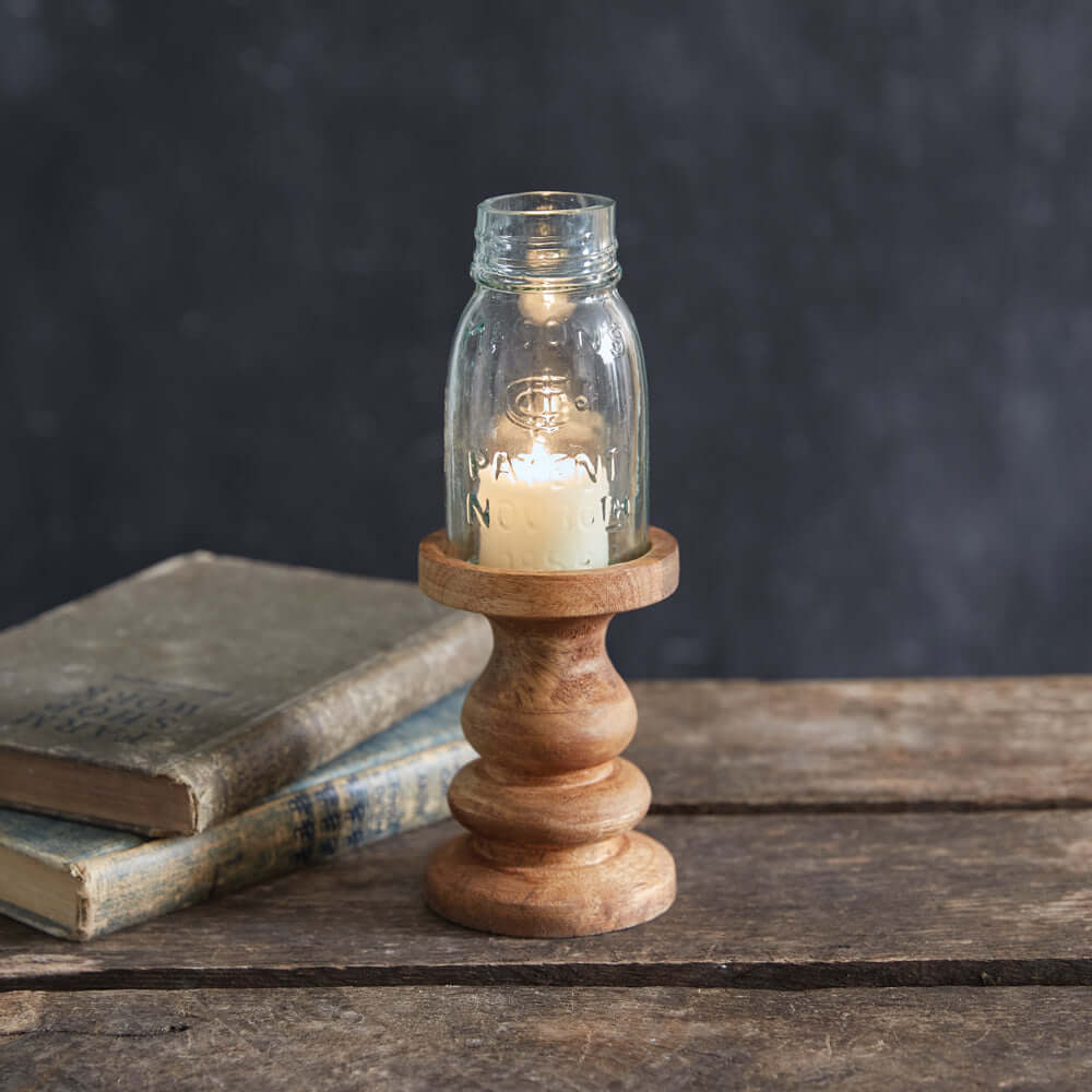 Rustic farmhouse candle holder with Mason jar on a wooden table, surrounded by vintage books.