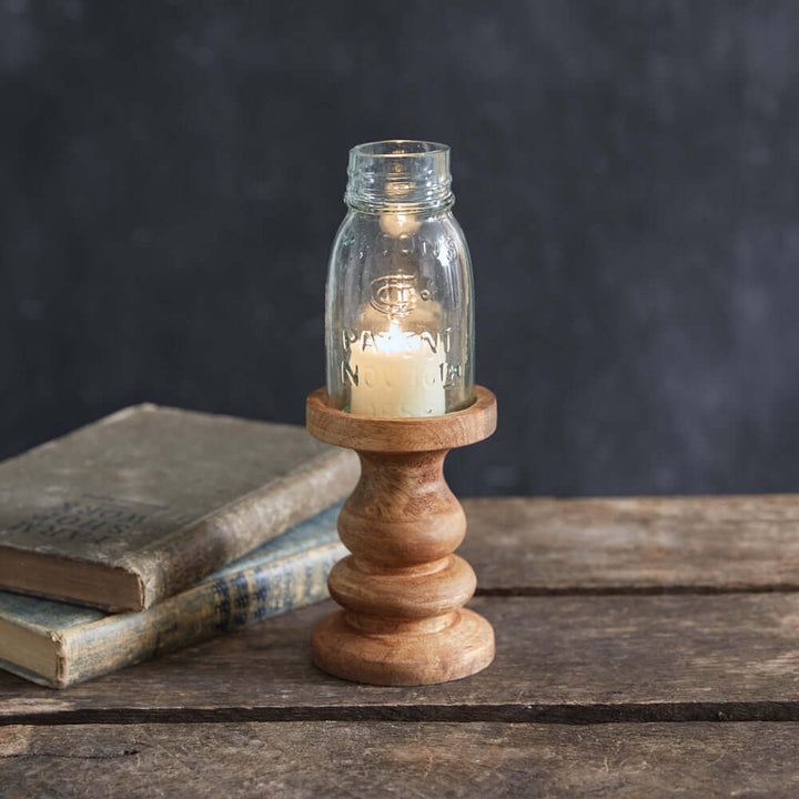 Rustic farmhouse candle holder with Mason jar on a wooden table, surrounded by vintage books.