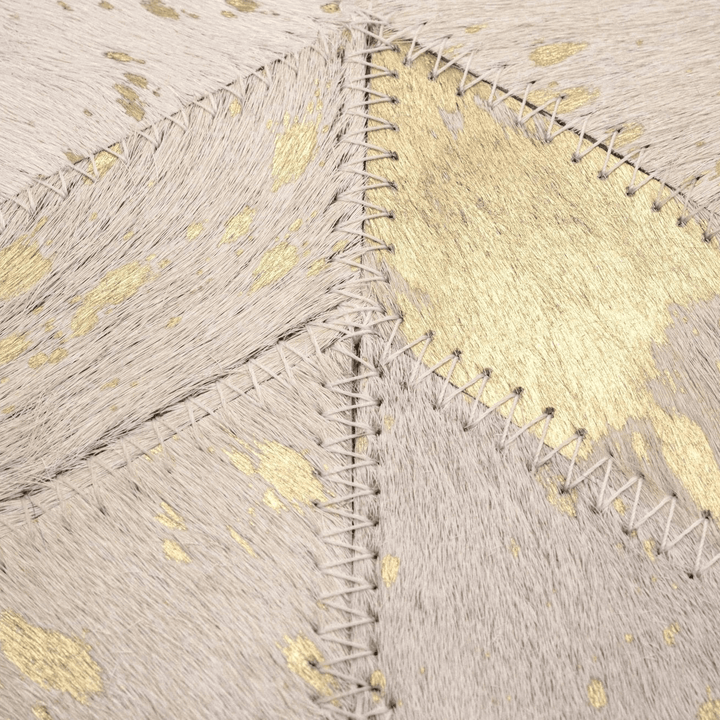 Close-up of cowhide pillow with gold accents and a visible seam.