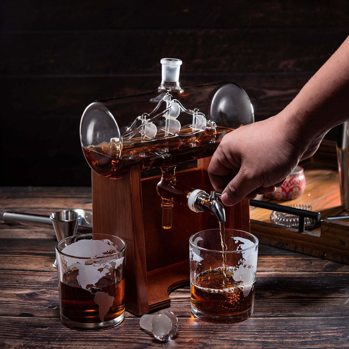 Hand pouring whiskey from a decanter into glasses on a wooden table.