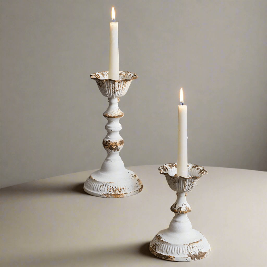 Distressed white metal taper candle holders set of 2 with candles glowing, showcasing vintage elegance and warmth.