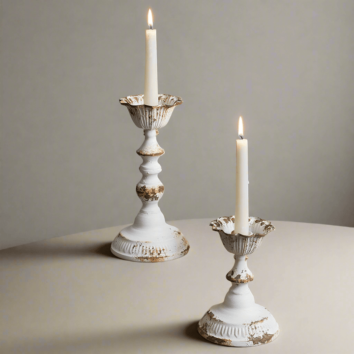 Distressed white metal taper candle holders set of 2 with candles glowing, showcasing vintage elegance and warmth.