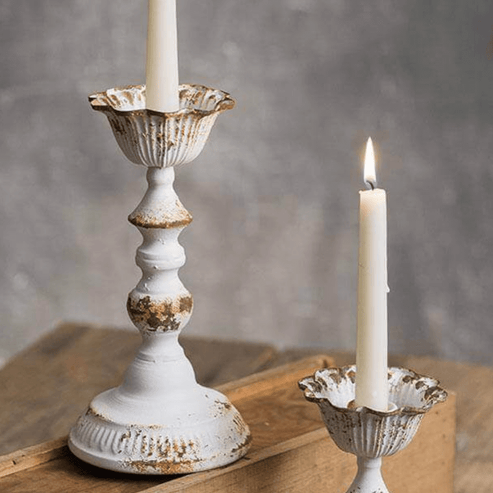 Distressed white metal taper candle holders set of 2, showcasing vintage elegance and warmth with lit candles.