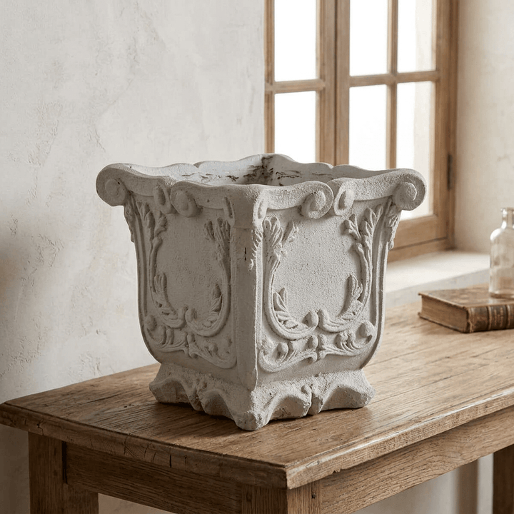 Duchess square laurel planter with a weathered pale gray finish and scrolled rim on a rustic oak console.