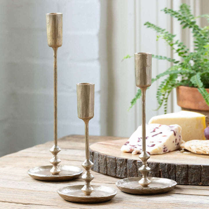 Vintage Antique Gold Iron Taper Candle Holders Set on table with cheese and plants, echoing colonial elegance and warmth.