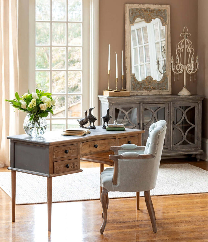 Elegant home office with vintage desk, chair, and antique gold iron taper candle holders displayed on a sideboard.