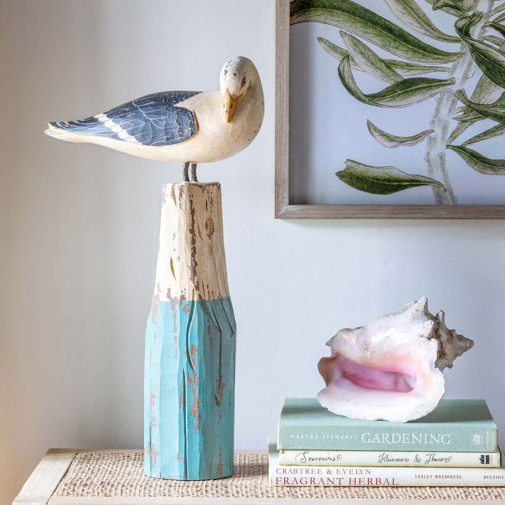 Vintage nautical seagull figurine perched on weathered wooden buoy, handcrafted in sea-washed turquoise and ivory hues, coastal decor
