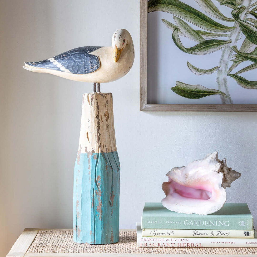 Vintage nautical seagull figurine perched on weathered wooden buoy, handcrafted in sea-washed turquoise and ivory hues, coastal decor
