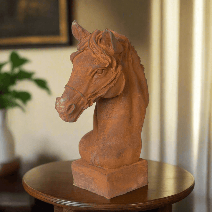 Aged cast iron horse head sculpture with weathered rust patina on a wooden table, perfect for equestrian decor.