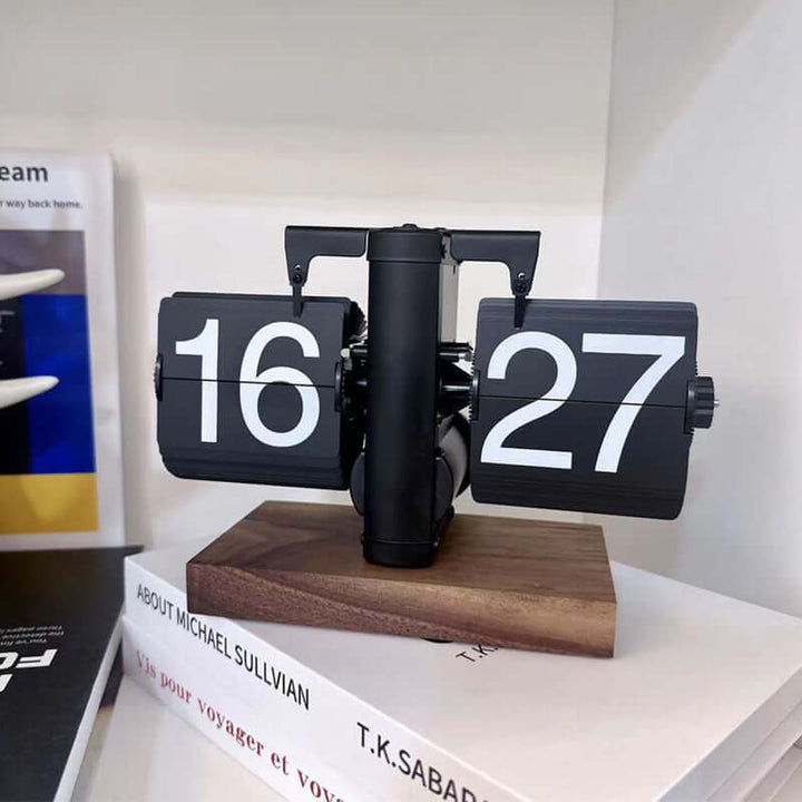 Flip clock with numbers 16 and 27 on a wooden base, placed on books.