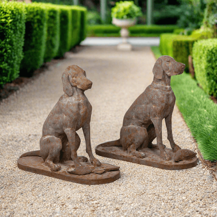 Rustic cast iron hunting dog sculptures set of 2 in garden setting.