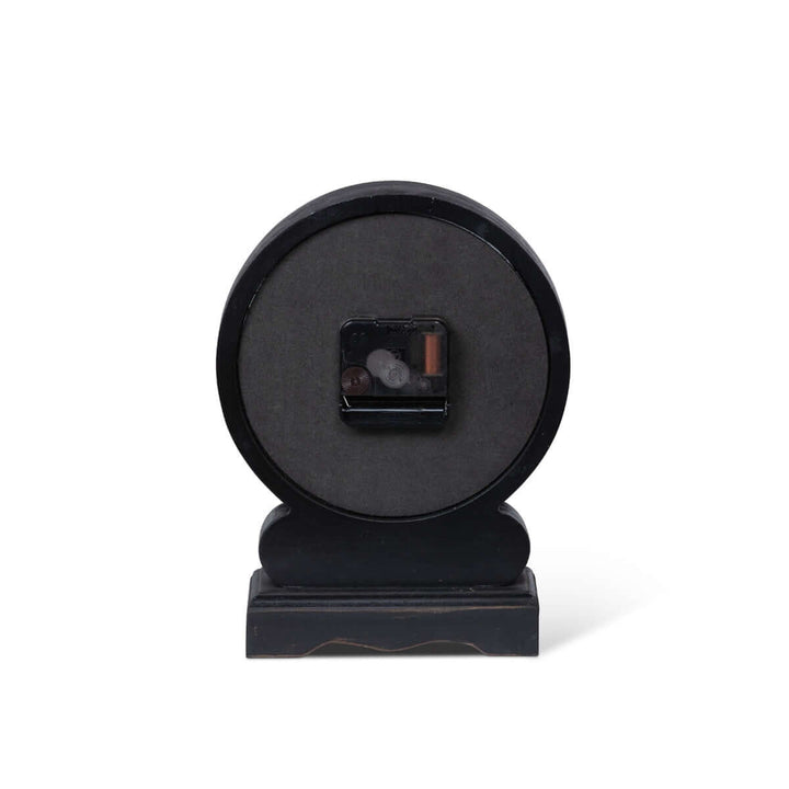 Back view of antique-style mantel clock with black finish and Roman numerals, showcasing its battery compartment.