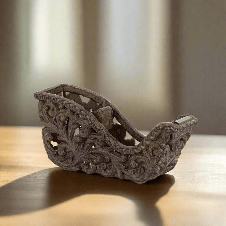 Ornate metal tape dispenser with Acanthus leaf design on a wooden desk, featuring antique-style sculpted detailing.
