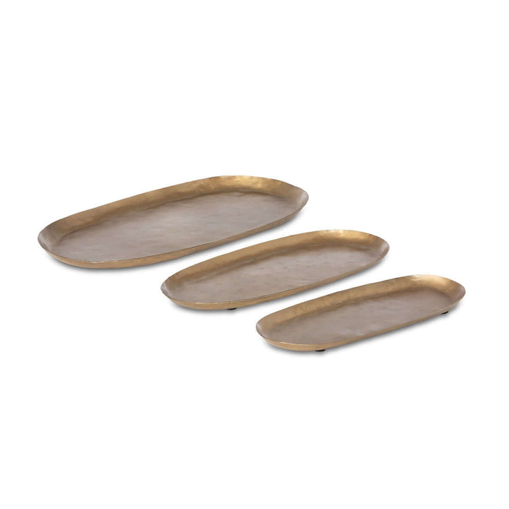 Set of three vintage gold iron serving trays with hand-hammered surfaces and upturned rims, ideal for elegant entertaining.