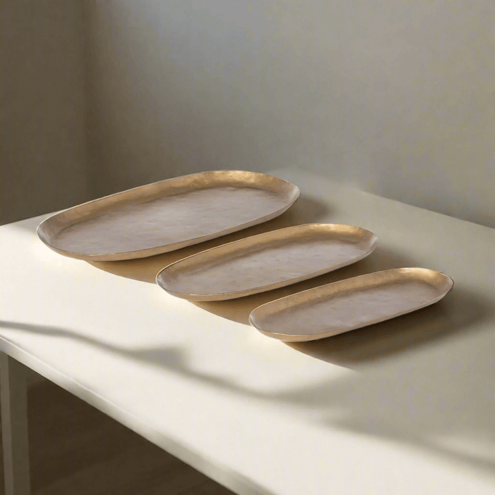 Vintage Gold Iron Serving Tray Set with three hand-hammered oval trays on table