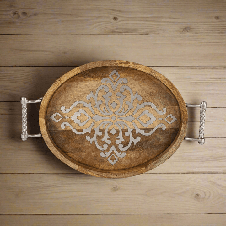 Rustic mango wood serving tray with ornate design and metal handles on a wooden surface, ideal for elegant gatherings.