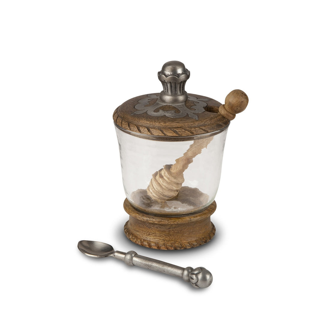 Decorative honey  jar with wooden lid and spoon on a white background