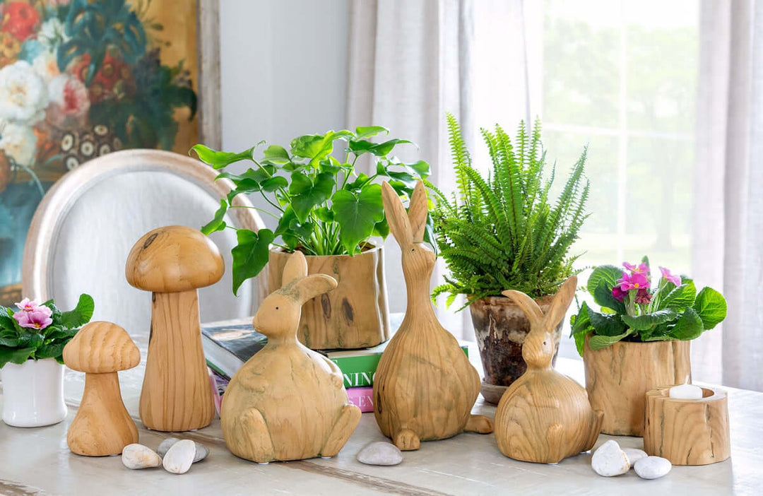 Faux Wood Tree Stump Planter on table with wood-like animal and mushroom decor, surrounded by plants and flowers, enhancing rustic home decor.