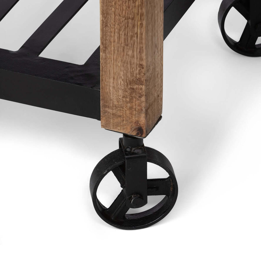 Close-up of vintage garden cart's rustic mango wood with black iron wheel, highlighting craftsmanship and durability.