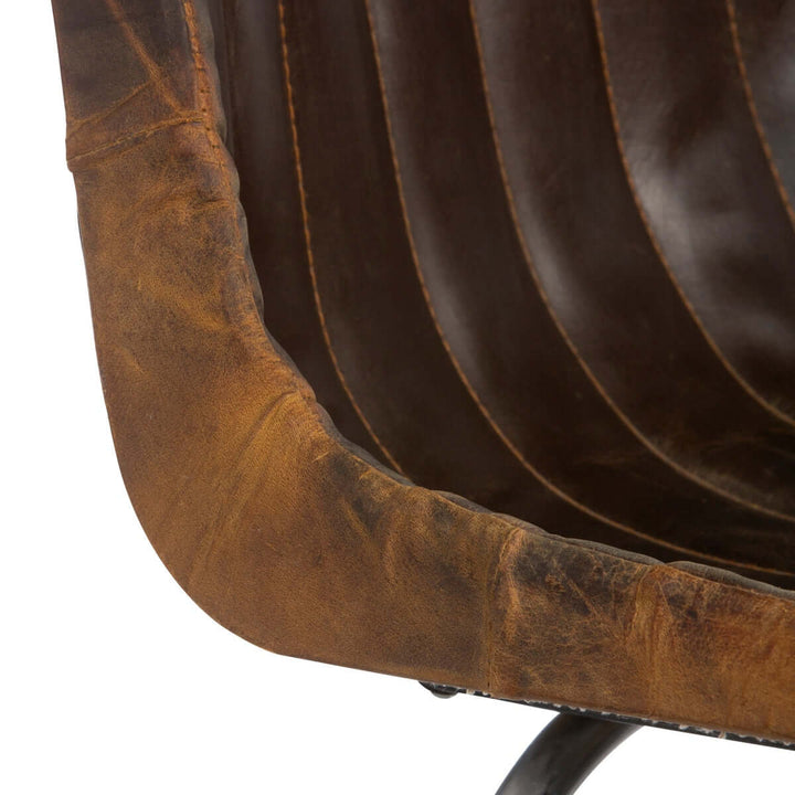 Close-up of vintage desk chair with aged leather upholstery and metal legs, showcasing its textured, distressed brown material.