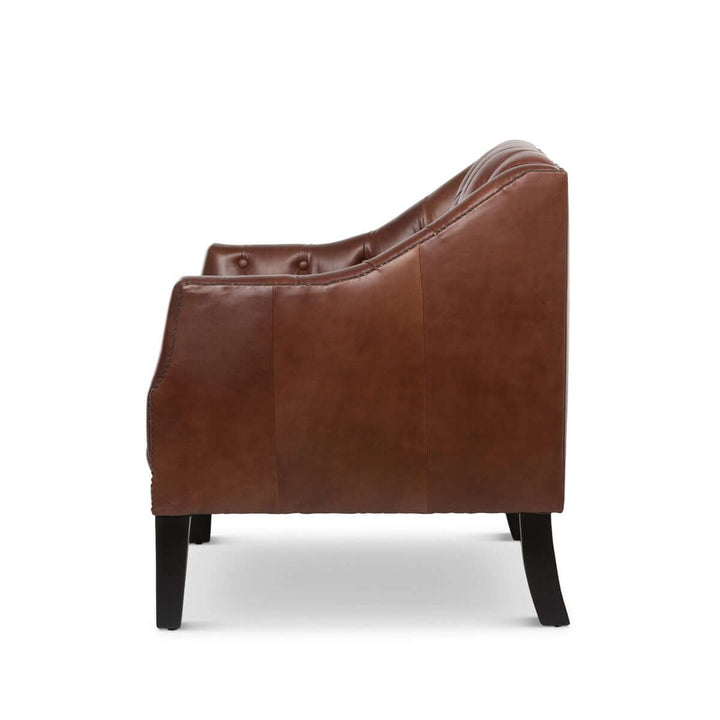Side view of tufted leather club chair in cordovan brown with nailhead trim, evoking vintage charm and luxury.