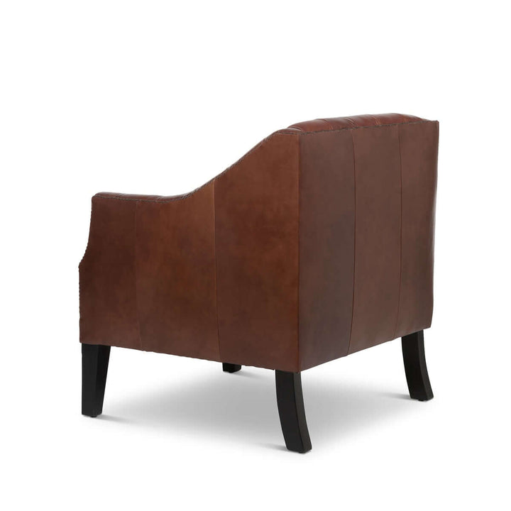 Back view of tufted leather club chair in cordovan brown with nailhead trim, showcasing sleek design and luxurious upholstery.