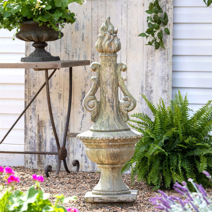Antique Grecian Garden Torch Statue with weathered finish in a lush garden setting