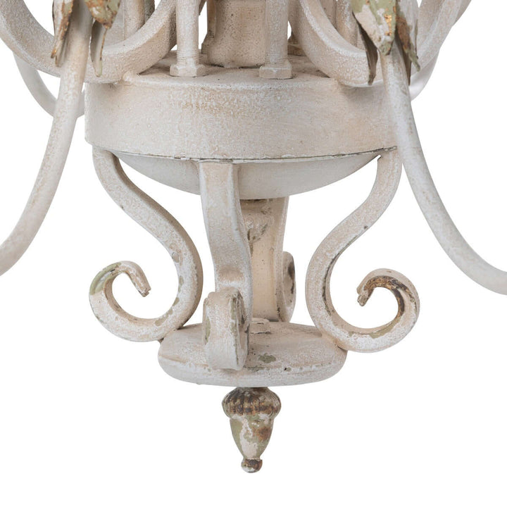 Detail of rustic French country chandelier with distressed cream finish and gold leaf accents, exuding vintage charm.