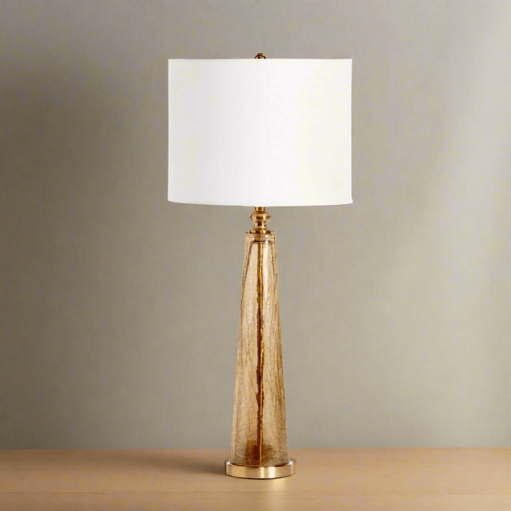 Crackled glass table lamp with white linen shade on wooden table showcasing elegant design and artistic craftsmanship.