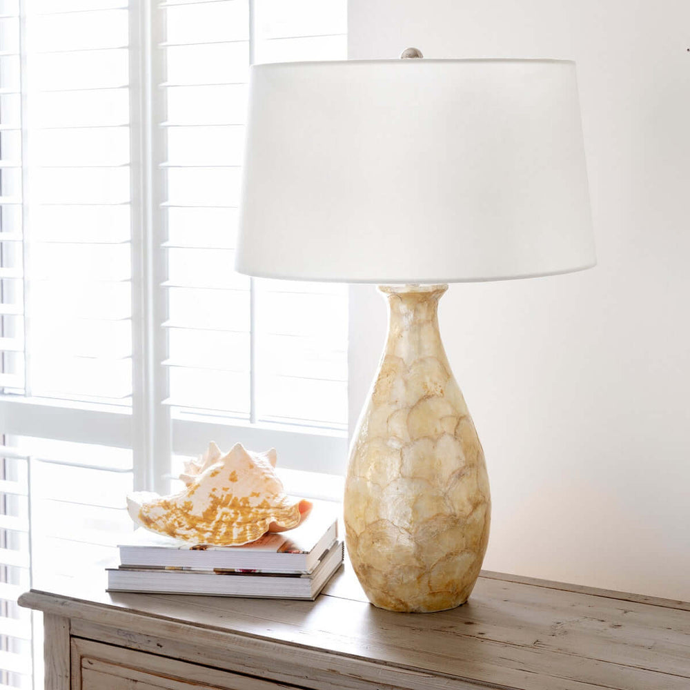 Coastal Pearl Capiz Shell Table Lamp with Linen Shade on wooden dresser by window.