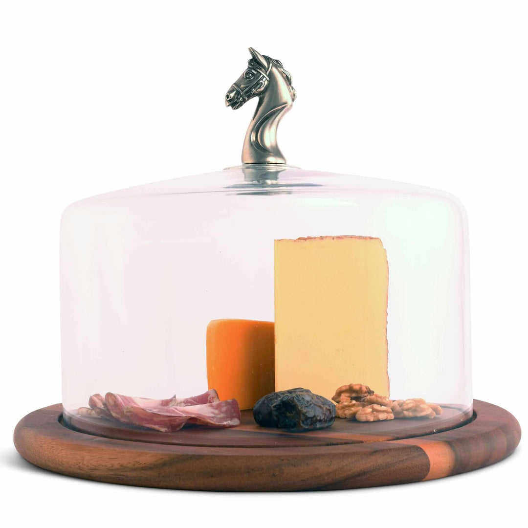 Glass cloche with a horse head finial, with cheese and other food on a white background
