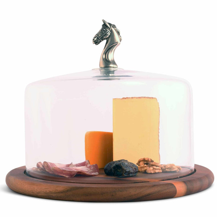 Glass cloche with a horse head finial, with cheese and other food on a white background