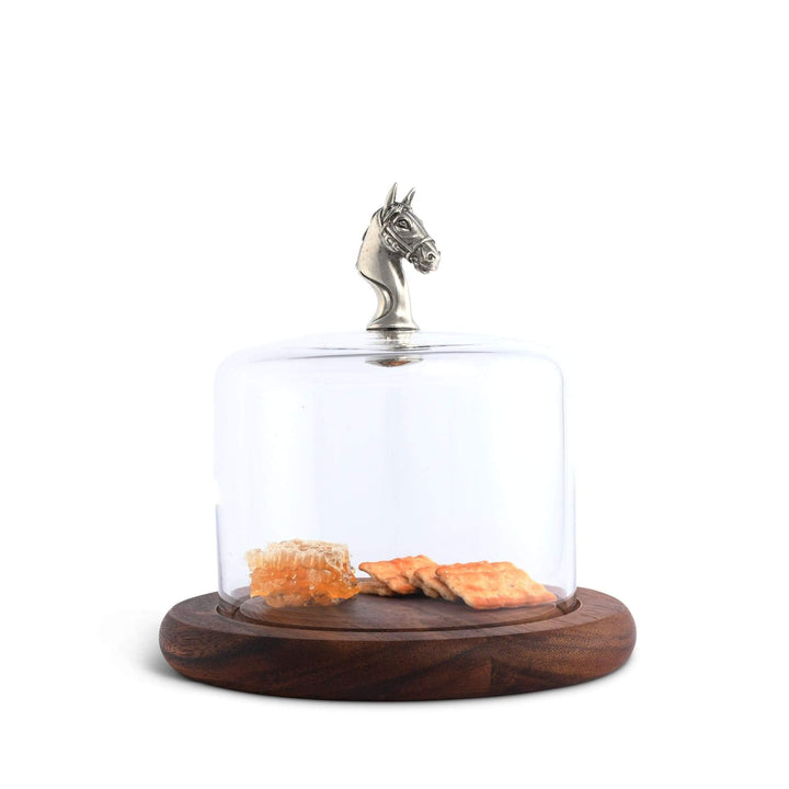 Glass dome with wooden base holding snacks and a horse head finial on a white background