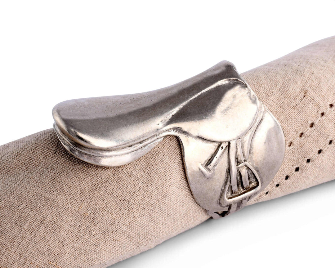 Silver saddle napkin ring on a beige napkin against a white background