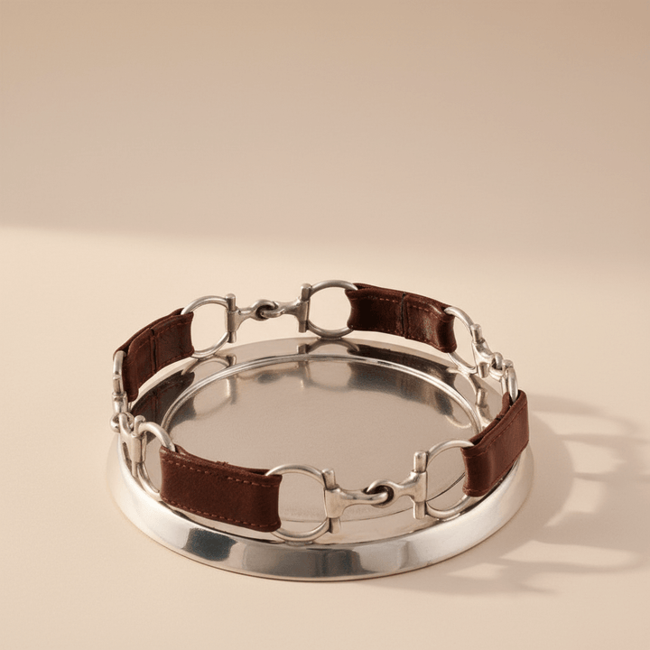 Silver horse bit with brown leather strap on a beige background