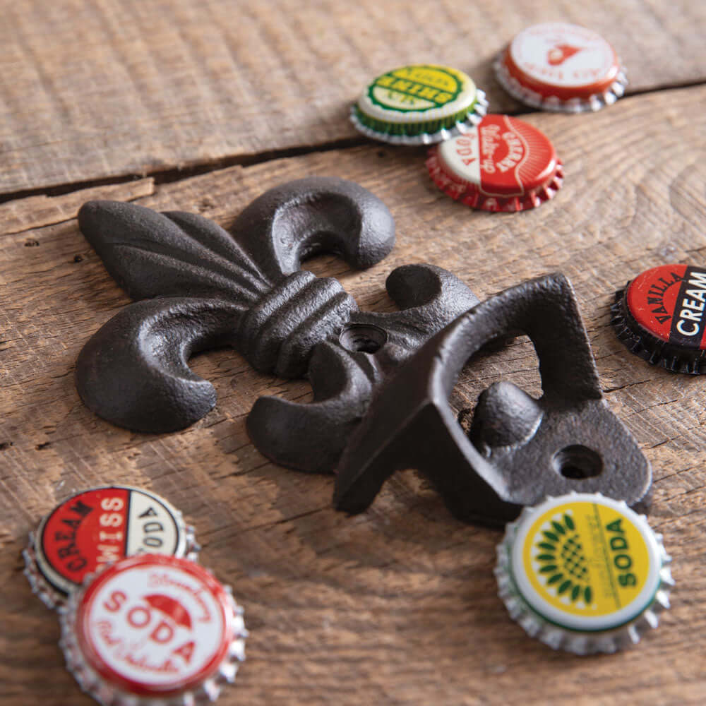 Fleur-de-Lis wall-mounted bottle opener on wooden surface with colorful bottle caps. Vintage cast iron design.