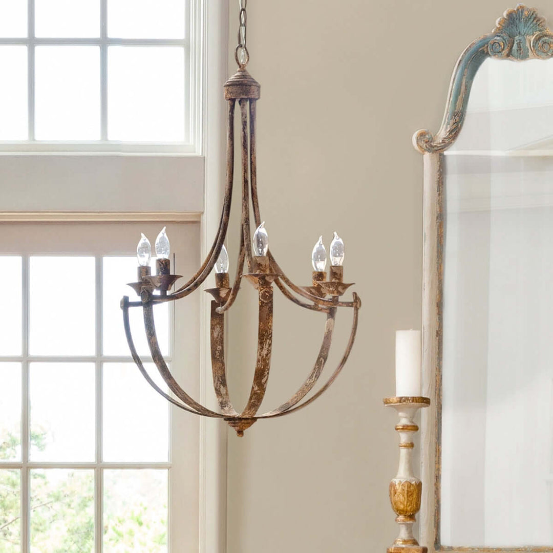 Vintage-style chandelier hanging in a room with a large mirror and window.