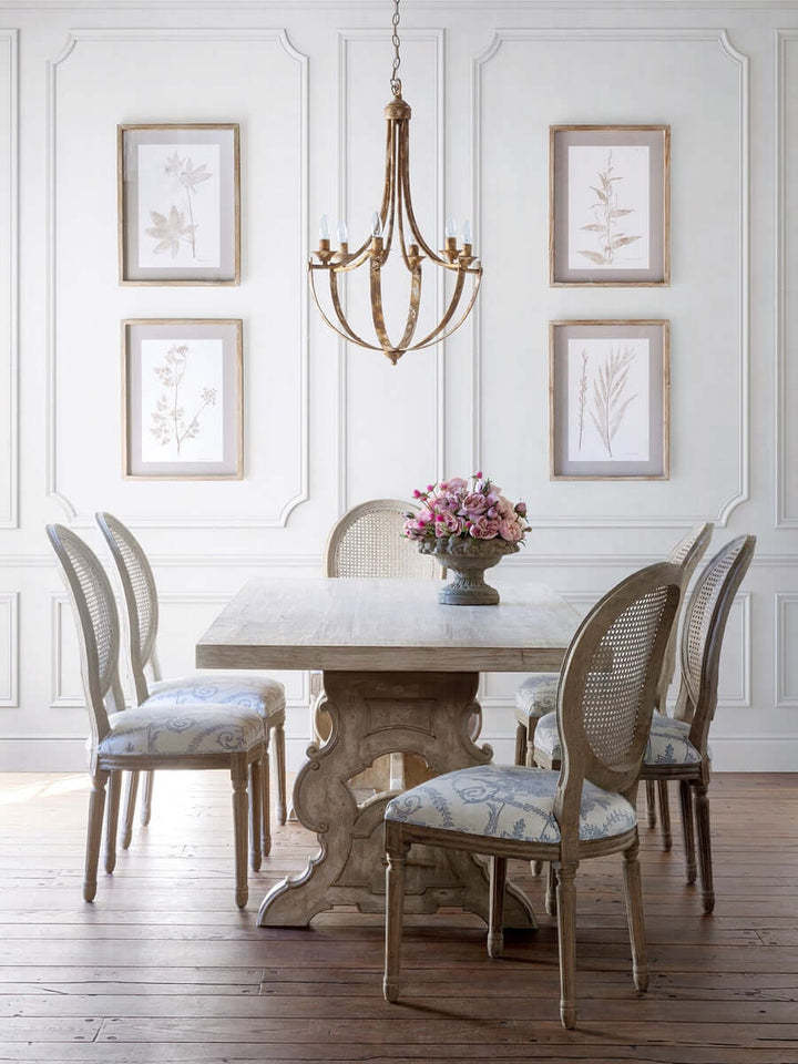 Dining room with marble table and chairs, floral arrangement, and framed pictures on the wall.