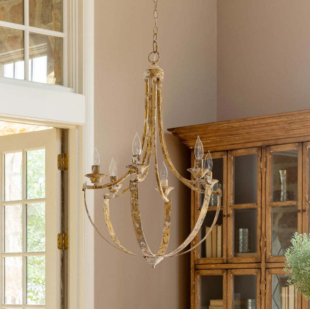 Decorative chandelier hanging in a room with a wooden cabinet and window.