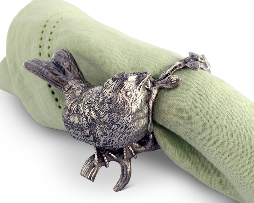 Silver bird-shaped napkin ring on a green napkin against a white background